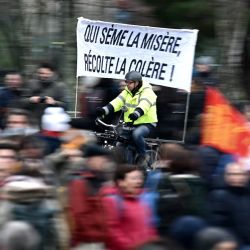 Un ciclista conduce con una pancarta en la que se lee "Quien siembra la miseria cosecha la ira" durante una manifestación en todo el país por la reforma de las pensiones propuesta por el Gobierno, en Nantes, Francia. | Foto:LOIC VENANCE / AFP