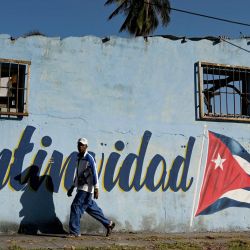 Un hombre pasa junto a un muro pintado con la bandera cubana que dice "Continuidad" en La Habana. | Foto:YAMIL LAGE / AFP