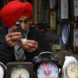 Un relojero repara un reloj en su puesto de una calle de Amritsar, India. | Foto:Narinder Nanu / AFP