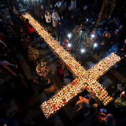 Creyentes encienden velas en una plataforma en forma de cruz cubierta con velas unidas a tarros de miel durante una ceremonia que marca el día de San Haralampi, patrón ortodoxo de los apicultores, en la Iglesia de la Santísima Virgen en Blagoevgrad, al este de Bulgaria. | Foto:NIKOLAY DOYCHINOV / AFP