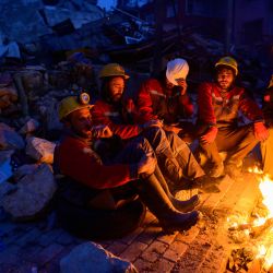 Rescatistas sentados junto a una hoguera en Hatay, Turquía, tras el terremoto de magnitud 7,8 que sacudió el sureste del país. | Foto:YASIN AKGUL / AFP
