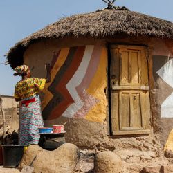 Una mujer decora una choza de barro durante el Festival Bogoia en Siby, Burkina Faso. - El Festival Bogoia se celebra para promover la construcción y el uso de materiales naturales y la decoración tradicional de las casas. | Foto:OUSMANE MAKAVELI / AFP