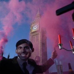 Un activista lleva una máscara que representa al primer ministro británico Rishi Sunak durante una protesta del grupo de justicia animal y climática Animal Rebellion, bloqueando la carretera en el puente de Westminster, en el centro de Londres. | Foto:DANIEL LEAL / AFP
