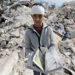 Un niño sirio, que perdió a su familia y también resultó herido como consecuencia del mortífero terremoto que sacudió Turquía y Siria, lleva un libro mientras permanece entre los escombros de la casa de su familia en la ciudad de Jindayris, en la parte de la provincia siria de Alepo controlada por los rebeldes. | Foto:BAKR ALKASEM / AFP