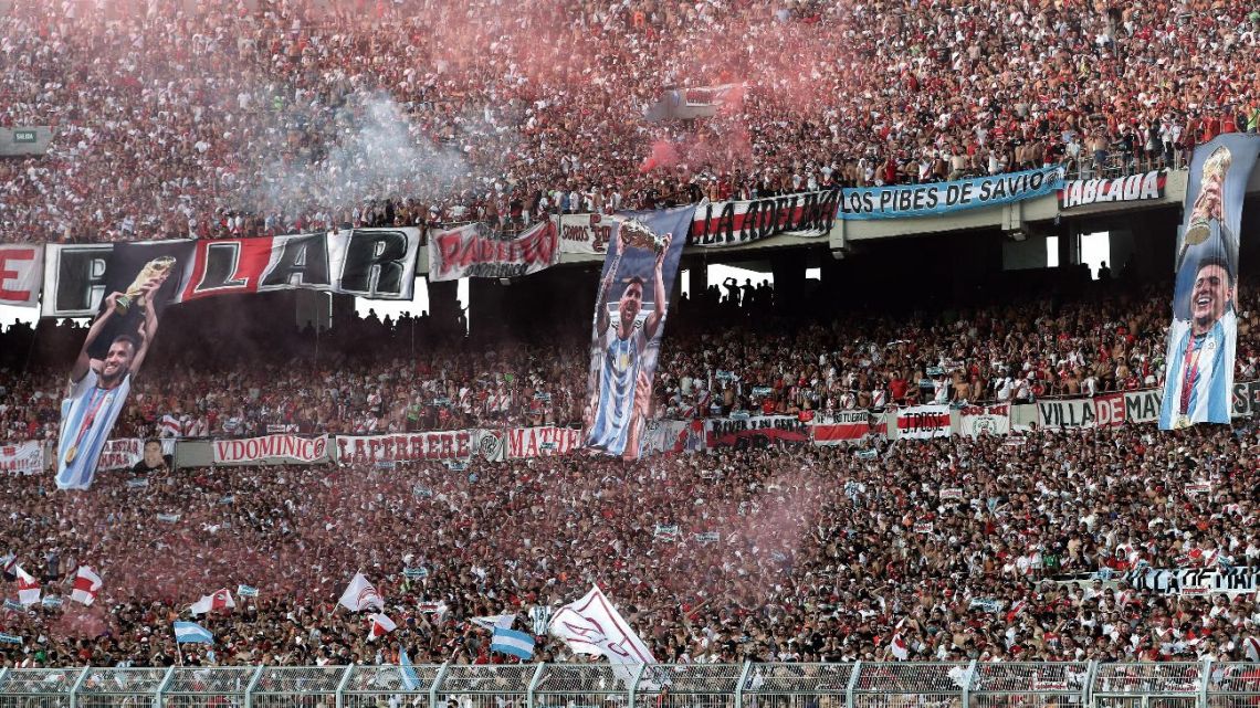 Banners depicting Argentina's German Pezzella, Lionel Messi and Enzo Fernández lifting the trophy after winning the Qatar 2022 World Cup are displayed on the stands as supporters of River Plate cheer for their team at El Monumental.