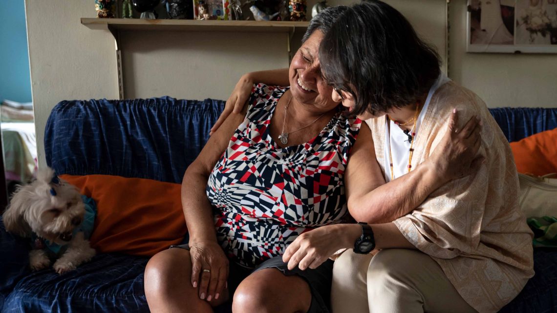 Maria Carolina Borges (R), a volunteer member of the CONVITE civil association, comforts Maria Dolores Jaime (L) during a visit to her apartment to discuss her general condition in the Petare neighborhood, Caracas on January 30, 2023.