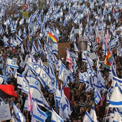 Varias personas se reúnen con banderas israelíes para protestar contra el proyecto de reforma judicial del gobierno cerca de la Knesset (parlamento) en Jerusalén. | Foto:AHMAD GHARABLI / AFP