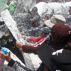 Personas que marchan en honor a los fallecidos durante los enfrentamientos con la policía en las manifestaciones contra la presidenta peruana Dina Boluarte, detienen la manifestación y juegan con la policía rociándoles espuma y agua como tradición carnavalesca en Puno, Perú. | Foto:Juan Carlos Cisneros / AFP