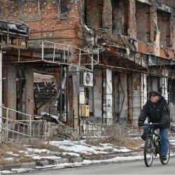 Un residente local pasa con su bicicleta por delante de edificios dañados y destruidos en Izyum, en medio de la invasión rusa de Ucrania. | Foto:SERGEY BOBOK / AFP