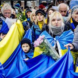 Con banderas ucranianas, la gente marcha desde fuera de la Embajada de Rusia, para conmemorar el primer aniversario de la invasión rusa de Ucrania, en La Haya. | Foto:ROBIN UTRECHT / ANP / AFP