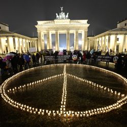 Un signo de la paz gigante se forma con velas frente a la Puerta de Brandeburgo en Berlín marcando el aniversario de la invasión de Rusia en Ucrania. | Foto:Tobias Schwarz / AFP