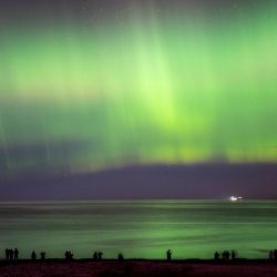 Las auroras boreales iluminan el cielo mientras los visitantes pasean por la playa de Hornbaek, en el norte de Sealand, Dinamarca. | Foto:Mads Claus Rasmussen / Ritzau Scanpix / AFP