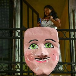 Una mujer en su balcón observa el carnaval de "Los huehues madrugadores" en el municipio de Totolac, estado de Tlaxcala, México. | Foto:PEDRO PARDO / AFP