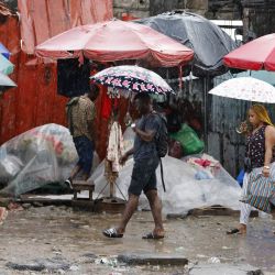 La gente camina en un mercado callejero durante una fuerte lluvia en la zona de Mont Bouet en Libreville, Capital de Gabón. | Foto:Ludovic Marin / AFP