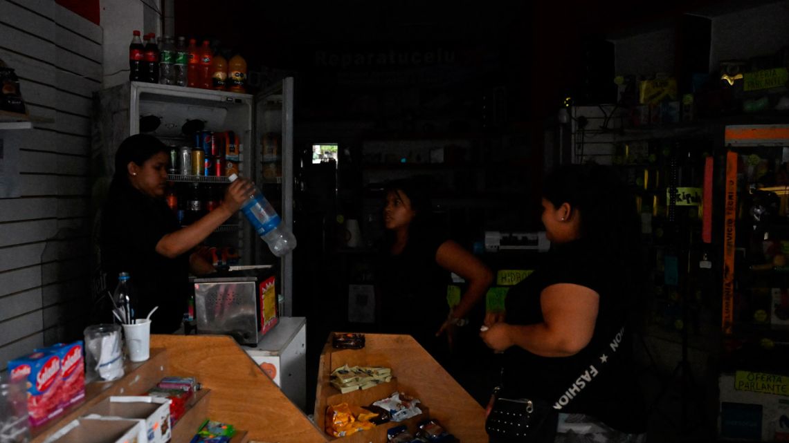 A woman buys water at shop in the dark in Buenos Aires on March 1, 2023, following an outage caused by a fire which affected the high-voltage system.