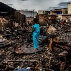 Un niño entre los restos de una casa quemada en una zona residencial de Plumpang, al norte de Yakarta, Indonesia, tras un incendio en un depósito de combustible estatal cercano gestionado por la empresa energética Pertamina. | Foto:ADITYA AJI / AFP