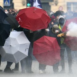 Un manifestante lanza fuegos artificiales a la policía antidisturbios mientras otros se protegen tras paraguas durante una manifestación en Rennes, al noroeste de Francia, como parte de una jornada de acción nacional contra la reforma de las pensiones del presidente francés y su aplazamiento de la edad legal de jubilación de 62 a 64 años. | Foto:FRED TANNEAU / AFP