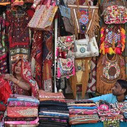 Una vendedora ordena su mercancía mientras espera a los clientes en el mercado de Nueva Delhi, India. | Foto:ARUN SANKAR / AFP