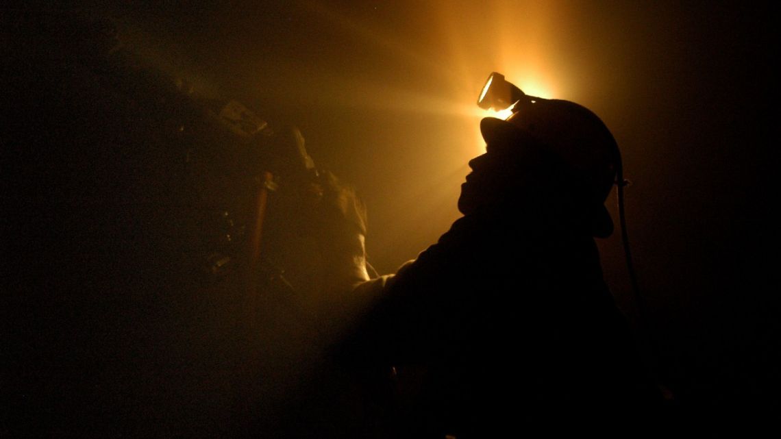 A worker operates a drilling machine underground at a mine.