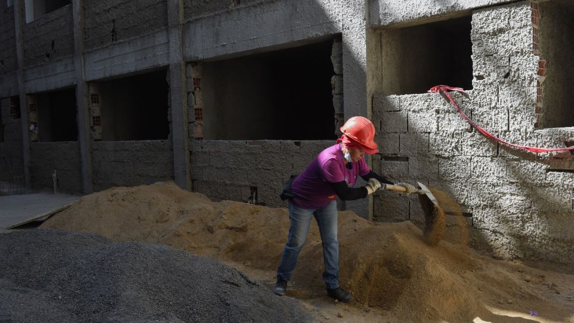 Worker Nancy Campos (55) loads dirt with a shovel during the construction of the residential building "Jorge Rodriguez Padre" in the Algodonal community in Caracas, Venezuela on February 22, 2023.