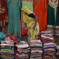 Una vendedora ordena su mercancía mientras espera a los clientes en el mercado de Nueva Delhi. | Foto:ARUN SANKAR / AFP