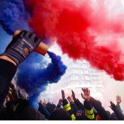 Miembros del sindicato de la energía CGT gesticulan y agitan bombas de humo azules y rojas activas mientras participan en una acción en una central eléctrica de Saint Denis, en la periferia norte de París, como parte de las protestas contra la reforma de las pensiones propuesta por el gobierno francés. | Foto:GEOFFROY VAN DER HASSELT / AFP
