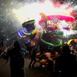 Personas se resguardan mientras otras corren alrededor de un tradicional "torito", armazón para fuegos artificiales hecho de papel maché, carrizo, madera y alambres en forma de toro, durante las celebraciones de San Juan de Dios realizadas en el marco de la Fiesta Nacional de la Pirotecnia, en Tultepec, Estado de México, México. | Foto:CLAUDIO CRUZ / AFP