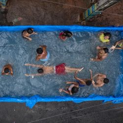 Los residentes de Aglomerado da Serra disfrutan de una piscina improvisada dentro de la caja de un camión durante las altas temperaturas del verano en Belo Horizonte, estado de Minas Gerais, Brasil. | Foto:DOUGLAS MAGNO / AFP
