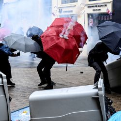 Manifestantes utilizan paraguas como protección de lanzamientos de gases lacrimógenos durante una manifestación en el marco de una jornada nacional de huelgas y protestas convocada por los sindicatos por la propuesta de revisión de las pensiones en Nantes, oeste de Francia. | Foto:SEBASTIEN SALOM-GOMIS / AFP