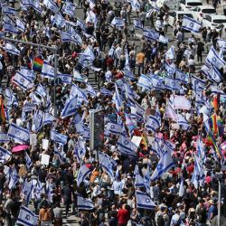Israelíes ondean banderas nacionales mientras protestan contra el controvertido proyecto de reforma judicial del gobierno en Tel Aviv. | Foto:JACK GUEZ / AFP