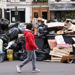 Un peatón pasa junto a contenedores de basura doméstica en una calle de París, que se han ido acumulando desde que los recolectores se declararon en huelga contra la propuesta de reforma de las pensiones del gobierno francés. | Foto:STEFANO RELLANDINI / AFP