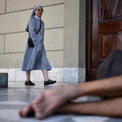 Una monja pasa junto a un indigente fuera de la Catedral Metropolitana de Buenos Aires. | Foto:LUIS ROBAYO / AFP