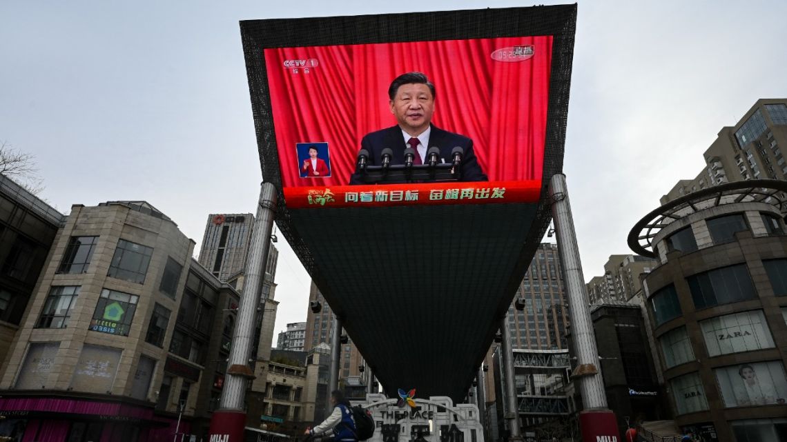 An outdoor screen shows a live news coverage of China’s President Xi Jinping delivering a speech during the closing session of the National People's Congress (NPC) at the Great Hall of the People, along a street in Beijing on March 13, 2023. 