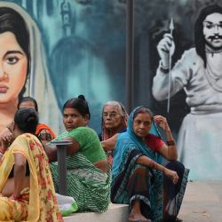 Mujeres sentadas frente a un mural con temática de Bollywood en Bombay, India. | Foto:SUJIT JAISWAL / AFP