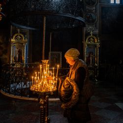 Una mujer enciende una vela durante el funeral por los voluntarios ucranianos asesinados en el monasterio ortodoxo de San Miguel de Cúpula Dorada, en Kiev, en medio de la invasión rusa de Ucrania. | Foto:DIMITAR DILKOFF / AFP