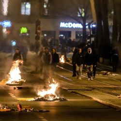 Un grupo de personas pasa junto a basura ardiendo durante una manifestación unos días después de que el gobierno impulsara una reforma de las pensiones a través del parlamento sin votación, utilizando el artículo 49,3 de la constitución en Lyon, este de Francia. | Foto:JEFF PACHOUD / AFP