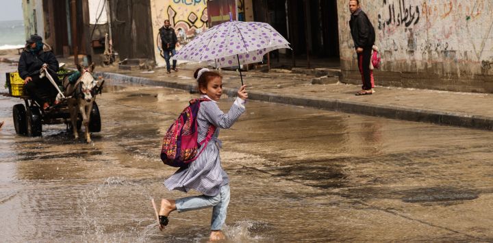 Palestinos caminan por una calle inundada tras las fuertes lluvias en el campo de refugiados de Al-Shati, en la franja de Gaza.