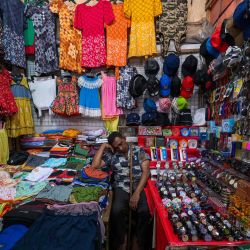 Un vendedor de ropa espera a los clientes en un mercado de Colombo, Sri Lanka. | Foto:ISHARA S. KODIKARA / AFP