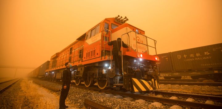 Esta foto muestra a un oficial de policía revisando vagones de tren en un puesto de control fronterizo durante una tormenta de arena en la ciudad de Erenhot, en la región septentrional china de Mongolia.