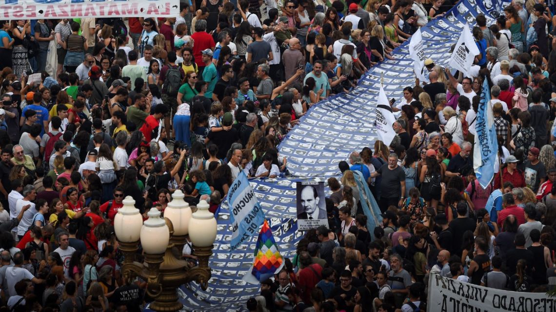 Hundreds carry a large banner with portraits of people who were disappeared during the 1976-1983 military dictatorship while heading to Plaza de Mayo Square in Buenos Aires to commemorate the 47th anniversary of the coup on March 24, 2023. 