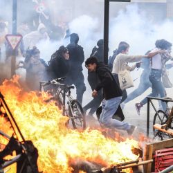 Manifestantes corren entre el humo de gases lacrimógenos junto a una hoguera callejera durante una manifestación en el marco de una jornada nacional de huelgas y protestas, una semana después de que el gobierno francés impulsara una reforma de las pensiones en el Parlamento sin someterla a votación, amparándose en el artículo 49.3 de la Constitución, en Toulouse, sur de Francia. | Foto:CHARLY TRIBALLEAU / AFP