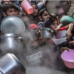Unos jóvenes extienden sus ollas y recipientes para recibir sopa preparada por el palestino Walid al-Hattab, mientras rompen el ayuno en el segundo día del mes sagrado musulmán del Ramadán en la ciudad de Gaza. | Foto:Mohammed Abed / AFP