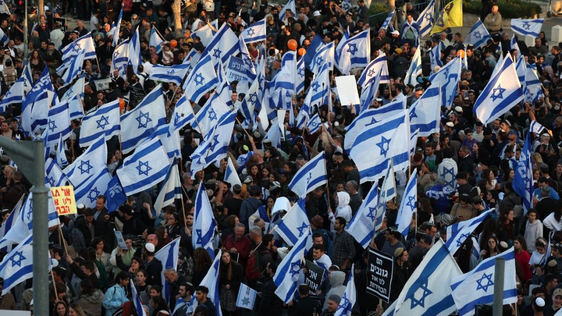 Protesters gather with national flags outside Israel's parliament in Jerusalem amid ongoing demonstrations and calls for a general strike against the hard-right government's controversial push to overhaul the justice system, on March 27, 2023. 