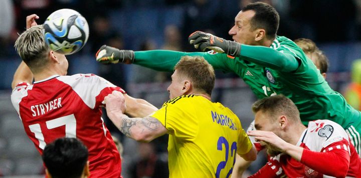 El arquero de Kazajistán Igor Shatski disputa la pelota con el defensor de Dinamarca Jens Stryger Larsen durante el partido de fútbol de clasificación para la UEFA Euro 2024 entre Kazajistán y Dinamarca en Astana.