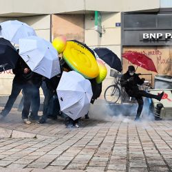 Un manifestante lanza un bote de gas lacrimógeno mientras otros usan paraguas como cobertores durante los enfrentamientos con la policía durante una manifestación después de que el gobierno impulsara una reforma de las pensiones a través del parlamento sin votación, utilizando el artículo 49.3 de la Constitución, en Nantes, oeste de Francia. | Foto:SEBASTIEN SALOM-GOMIS / AFP