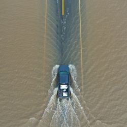 Una imagen aérea muestra una camioneta conduciendo a través de las aguas de inundación en la carretera 43 en el Valle Central durante una tormenta de invierno en el condado de Tulare cerca de Allensworth, California. | Foto:Patrick T. Fallon / AFP