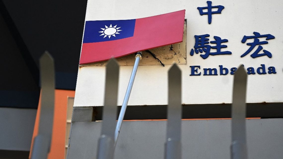 A worker takes down Taiwan's flag of the facade of the country's Embassy in Tegucigalpa on March 27, 2023.