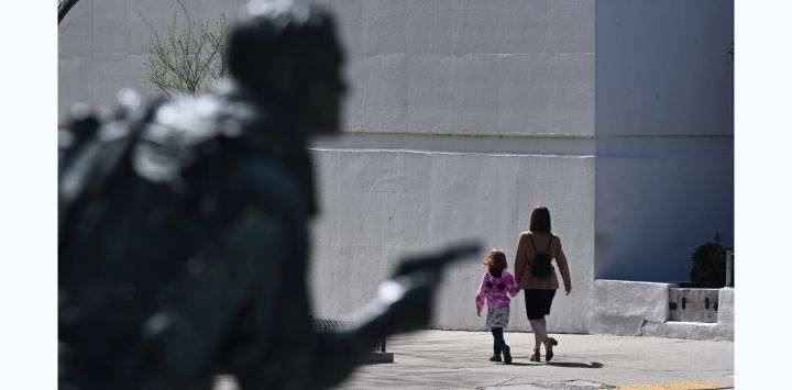 Un grupo de personas pasa junto a una estatua cerca del Capitolio del Estado de Tennessee en Nashville, Tennessee, tras un tiroteo en una escuela, donde tres estudiantes y tres miembros del personal murieron.