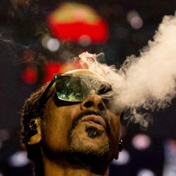 El rapero estadounidense Calvin Cordozar Broadus Jr alias Snoop Dogg echa humo mientras actúa en el escenario del Accor Arena de Bercy, en París. | Foto:Anna Kurth / AFP