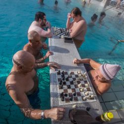 Turistas y visitantes juegan al ajedrez en el agua del balneario Szechenyi de Budapest, Hungría. - Los grandes baños termales húngaros luchan por mantenerse a flote, golpeados por el aumento de la factura energética. | Foto:FERENC ISZA / AFP